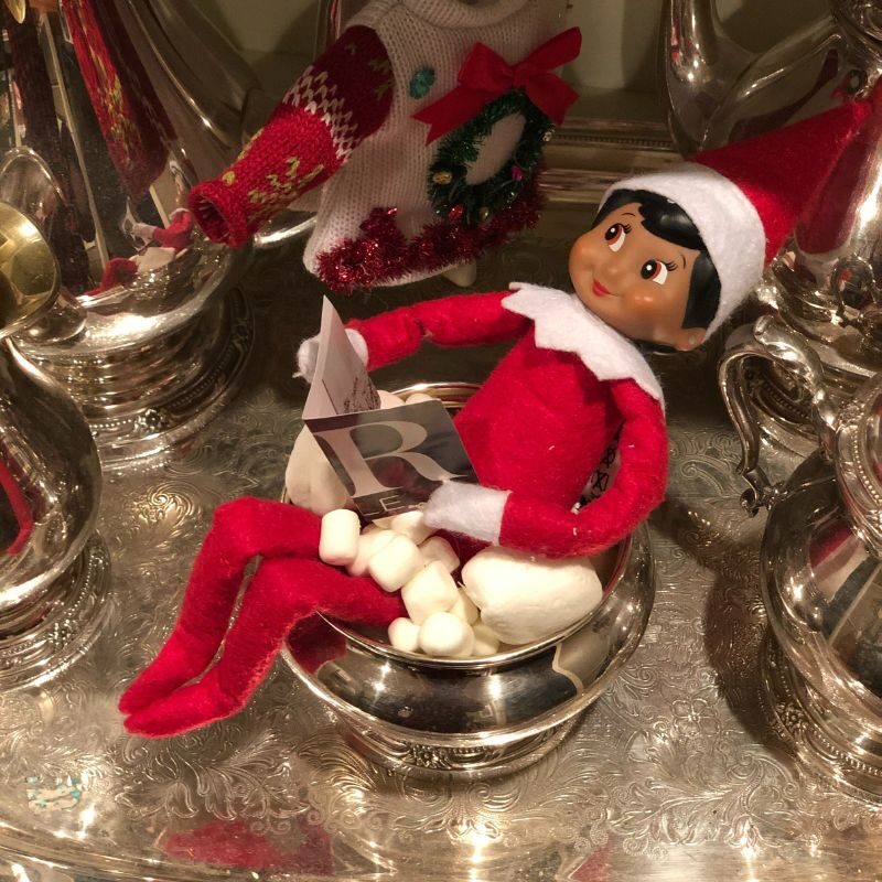 An Elf on the Shelf sits in a silver bowl full of marshmellows.